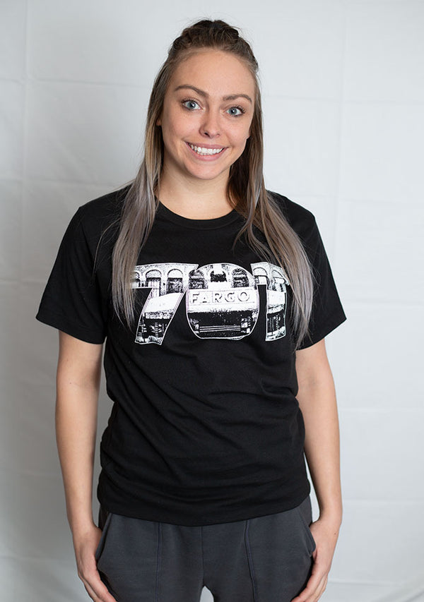 A Black crew neck short sleeved tee with white graphic. the numbers 701 with the Fargo Theater appear on the front of the shirt.