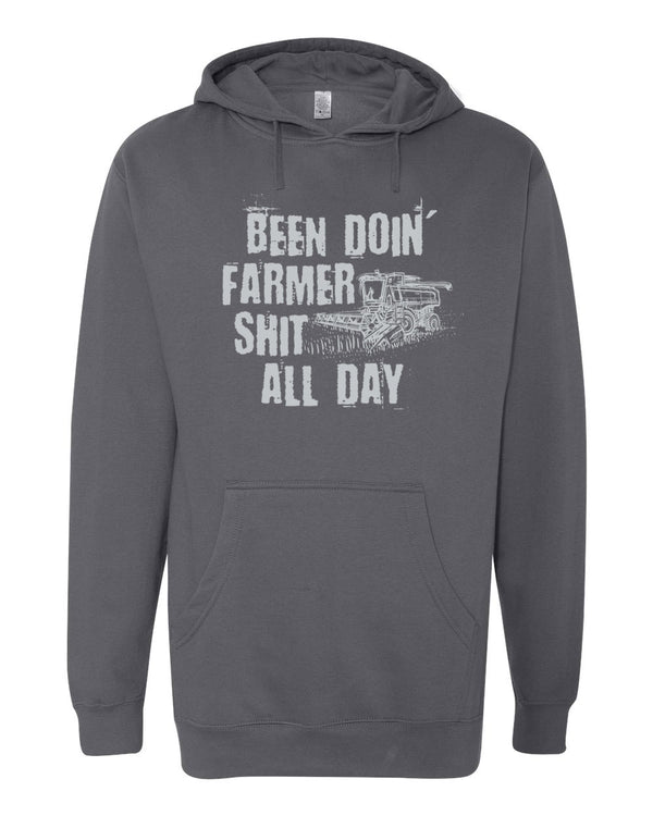 Dark Grey hooded sweatshirt. Graphic in white is a tractor plowing a field. Design reads Been Doin' Farmer Shit All Day.