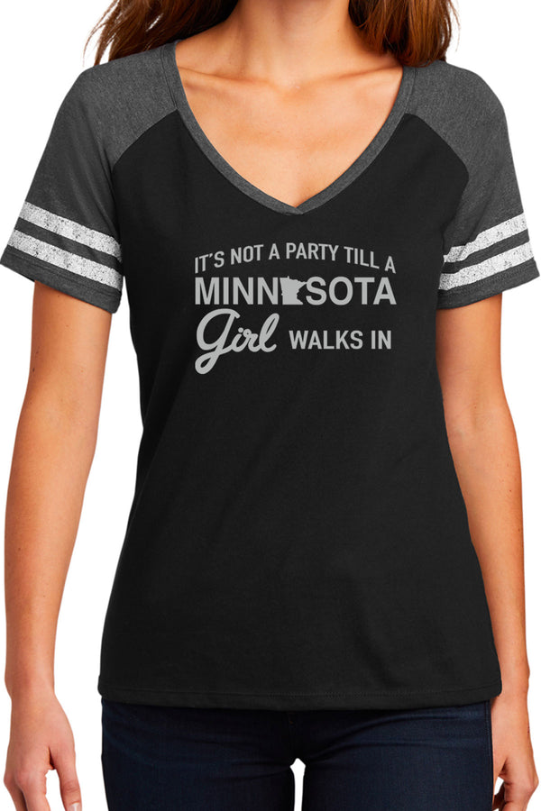 Woman wearing a game day styled, V neck short sleeved tee shirt. Black shirt, grey sleeves, two white stripes on each sleeve. Front white graphic reads It's Not A Party Till A Minnesota Girl Walks In. Sizes small to 3X-Large.