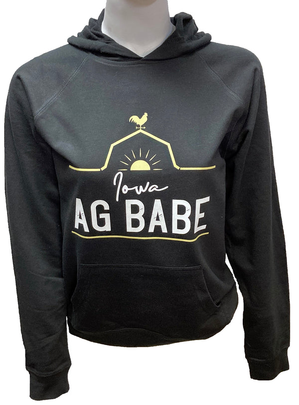 A mannequin wearing a unisex, black pouch front hooded sweatshirt. A front graphic in gold and white  shows a barn roof line, rooster and sun with sun rays. Just under the roof line large lettering reads Iowa Ag Babe