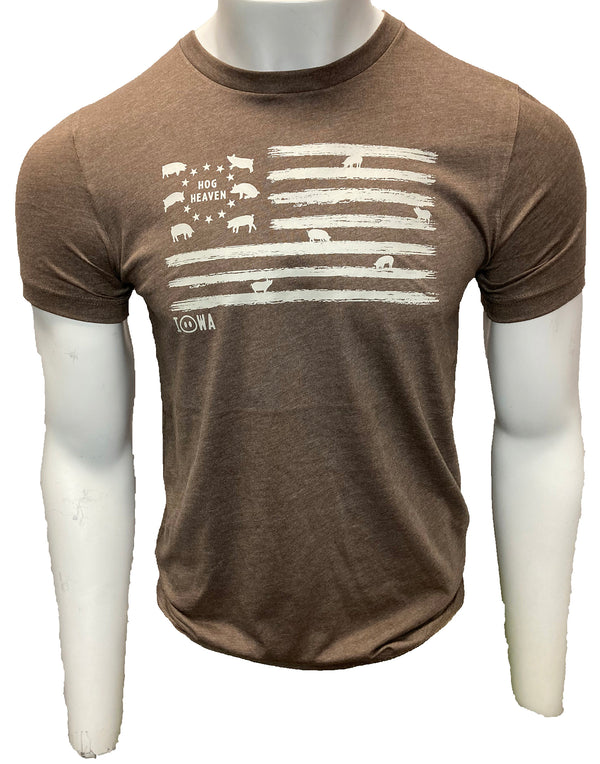 A male mannequin wearing a Heather Brown, unisex, blended fabric short sleeved tee shirt. The Light Grey front flag design shows hogs in the stars field and standing on the flag stripes. Wording is Iowa Hog Heaven. Available in sizes Small to 3X-Large.