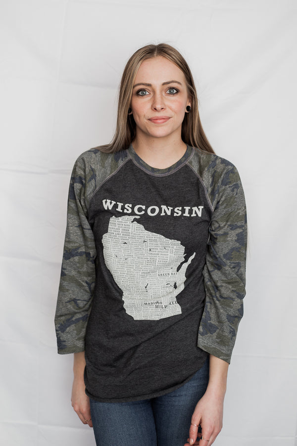 A woman wearing a Dark Grey Heather, Camo sleeved unisex baseball tee with raglan sleeves. On the shirt front is a light grey graphic of the state of Wisconsin and its cities. Sizes small to 3X-Large. A Scratchpad Tees original design.