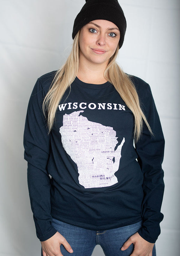 A woman wearing a 100 percent cotton, midnight navy long sleeved, crew neck tee shirt. The white front graphic is of Wisconsin and its cities. A scratchpad Tees original design, this shirt is available in sizes small to 3X-Large.