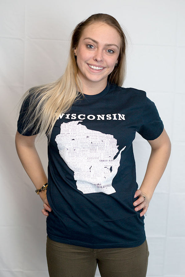 A woman wearing a unisex sized, Midnight navy, crew neck, 100 percent cotton, short sleeve tee. Front white graphic is of Wisconsin and its cities. Sizes small to 3X-Large. A Scratchpad Tees original design.