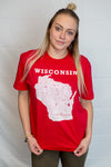 A woman wearing a unisex sized, red, crew neck, 100 percent cotton, short sleeve tee. Front white graphic is of Wisconsin and its cities. Sizes small to 3X-Large. A Scratchpad Tees original design.