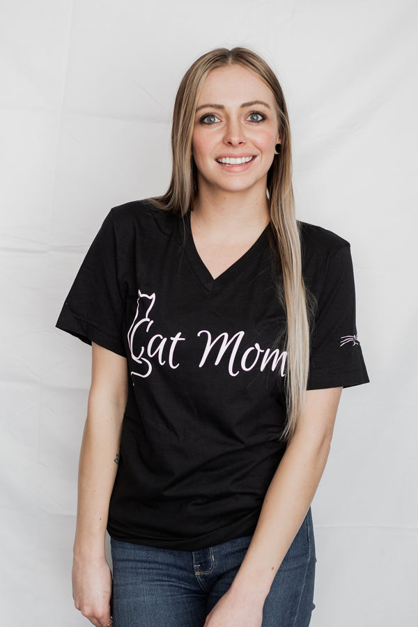 A unisex Black V-neck tee with the words Cat Mom in white ink on shirt front. Cat nose and whiskers are on the left sleeve