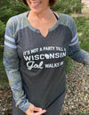 A woman wearing a ladies cut, semi-fitted, long sleeved, notched collar jersey styled tee shirt. Dark grey body with Camo sleeves. Front white graphic reads It's Not A Party Till A Wisconsin Girl Walks In. Available in sizes small to 2X-Large.