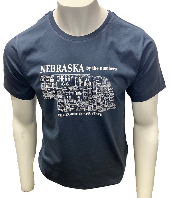 A male mannequin wearing a Steel Blueo, unisex, 100 percent cotton, short sleeved tee. The white front graphic is a map of Nebraska a cities by name and number. Wording reads Nebraska the Husker Stateoun. Available in sizes Small to 3 X-Large