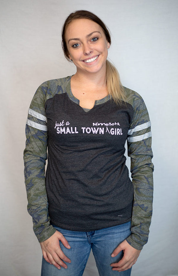 A ladies cut long sleeve notched collar jersey styled tee shirt. Dark grey body with Camo sleeves . Front white graphic says Just A Small Town Minnesota Girl .