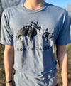 A male model wearing a Flint Blue Trim-blend crew neck tee shirt. The front graphic includes a charging buffalo launching a tourist family up in the air. The caption reads; Tossin' Tourists since 1889 in North Dakota.
