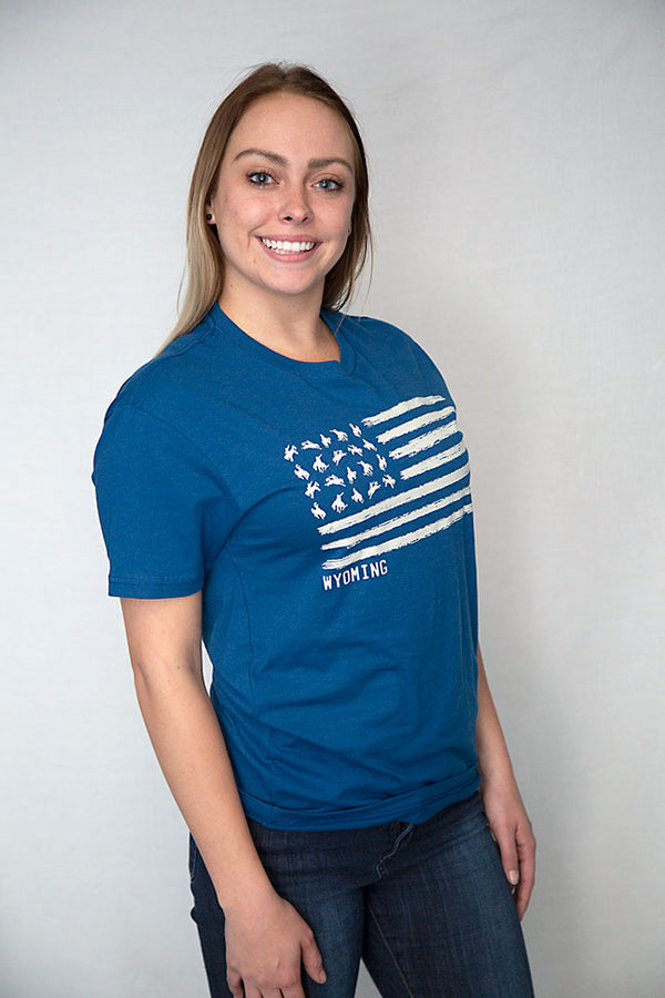 A Cool Blue colored crew neck unisex tee shirt. The graphic resembles the U.S. flag with images of Bucking Broncos in the stars field. The word WYOMING is placed directly under the graphic.