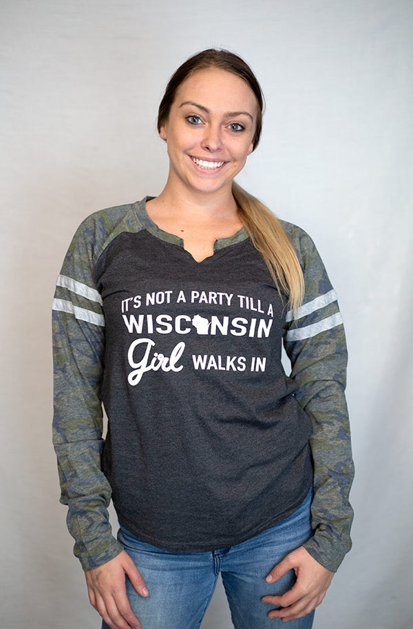 A woman wearing a ladies cut, semi-fitted, long sleeved, notched collar jersey styled tee shirt. Dark grey body with Camo sleeves. Front white graphic reads It's Not A Party Till A Wisconsin Girl Walks In. Available in sizes small to 2X-Large.